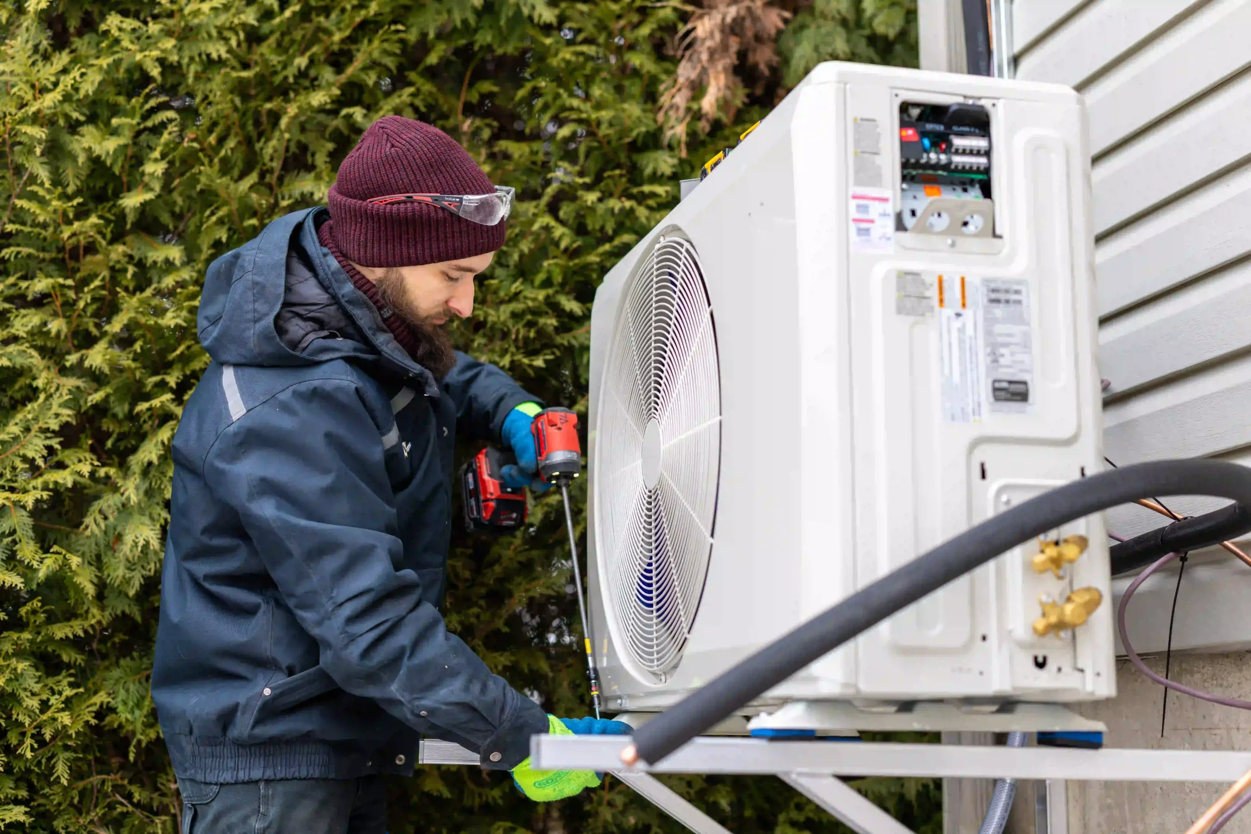 Technicien installant une unité extérieure de thermopompe résidentielle en hiver
