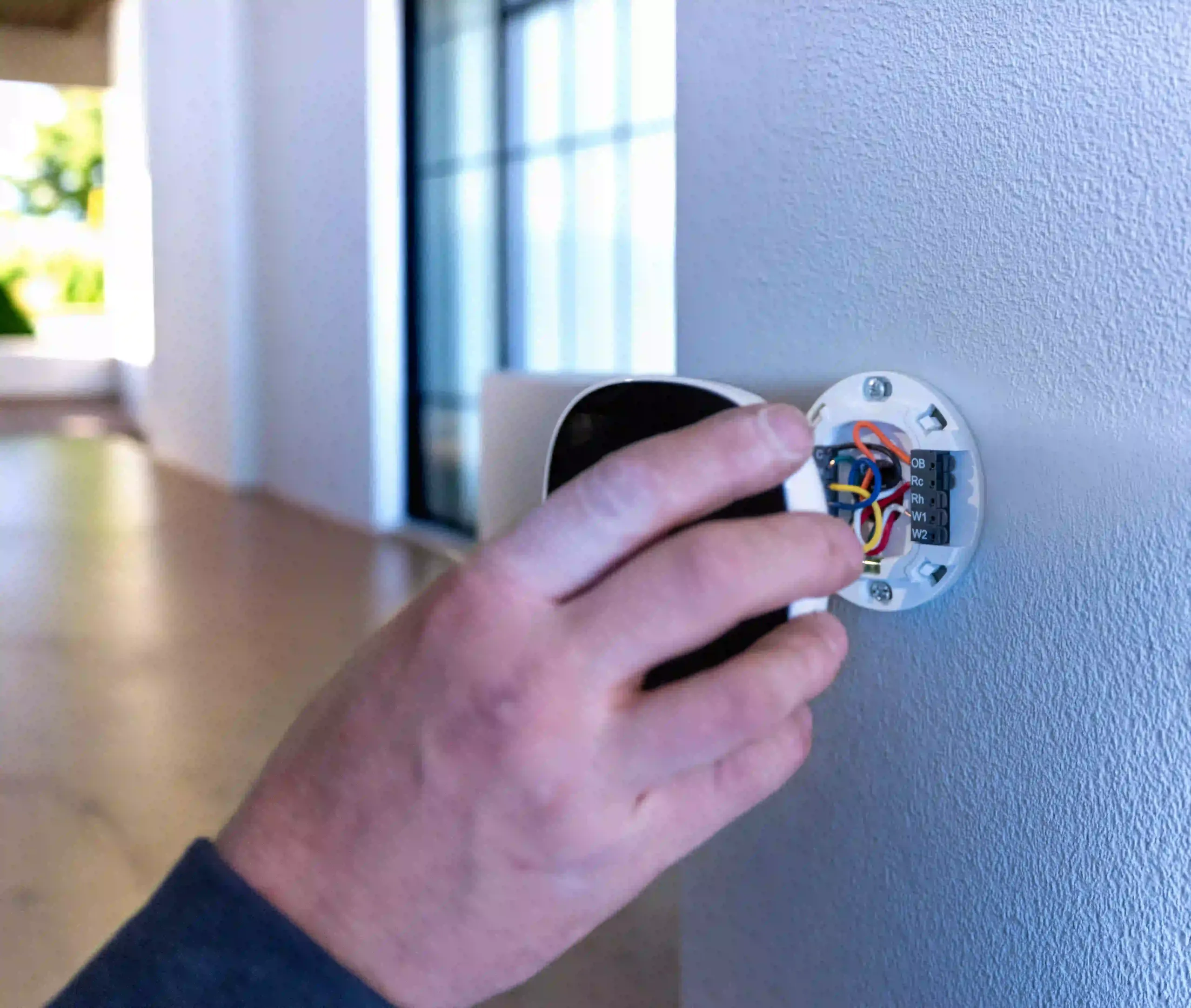 Installation et raccordement d’un thermostat résidentiel Technicien branchant un thermostat mural pour un système de chauffage et climatisation résidentiel
